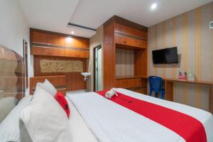 a bedroom with a bed with a red and white blanket at RedDoorz near RSIA Andini Pekanbaru in Pekanbaru