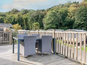 a table and chairs on a deck with a fence at Elm Lodge in Ilfracombe
