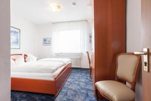 a hotel room with a bed and a chair at TM Hotel Dortmund Airport in Holzwickede
