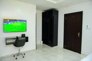 a room with a chair and a television on a wall at Cc & Cg Homes Luxury 4-Beds Apart Abuja-24Hrs Power in Abuja