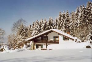 una casa cubierta de nieve frente a los árboles en FW Winterer en Zwiesel