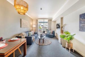 un soggiorno con un divano blu e un tavolo di King Suite Dreams - Poolside Living on the Esplanade a Darwin