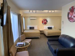 a hotel room with two beds and a couch at 755 Regal Court Motel in Dunedin