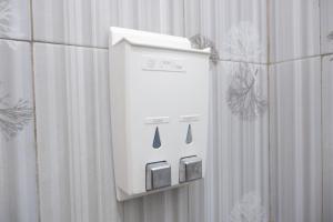a white soap dispenser on a bathroom wall at Griya Limasan Gunung Kidul in Wonosari