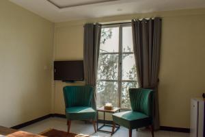 um quarto com duas cadeiras, uma mesa e uma janela em The Point by Roomy, Thandiani em Abbottabad