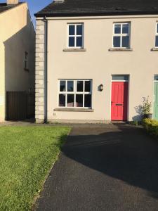 a white house with a red door and a driveway at Modern 3-bedroom townhouse in the Mournes in Newry