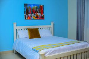 a bedroom with a bed with a blue wall at Keisha Luxury Furnished Apartment Bukoto in Kampala