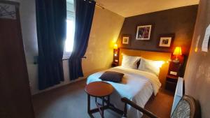 a bedroom with a bed and a table and a window at Hôtel 1er Consul Rouen in Rouen
