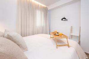 biała sypialnia z łóżkiem z drewnianym stołem w obiekcie Amargura City Center Apartment w Maladze