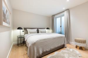 ein weißes Schlafzimmer mit einem Bett und einem Fenster in der Unterkunft Ferienhaus Finoah - Leben, Luxus, Leichtigkeit hinter der Duene in Westerland Sylt in Westerland