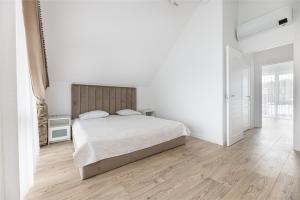 a white bedroom with a bed and a wooden floor at Sea House 2N in Palanga