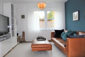 a living room with a brown leather couch and a television at Ferienwohnung "Moi Tied" 35222 in Hesel