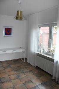 Cette chambre blanche dispose d'une fenêtre et de carrelage. dans l'établissement Ferienwohnung "Moi Tied" 35222, à Hesel