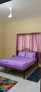 uma cama roxa num quarto com uma janela em HOMESTAY KAKMAH em Jasin