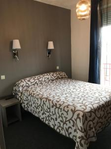 een slaapkamer met een bed, een lamp en een raam bij Hôtel Océan in Lourdes