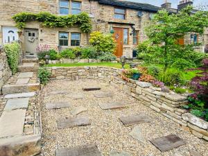 un jardin avec une passerelle en pierre en face d'une maison dans l'établissement Tynedale, à Padiham