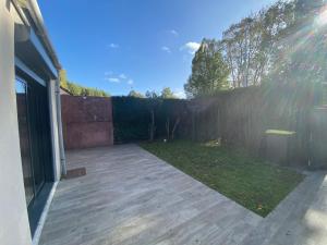 a backyard with a fence and a wooden patio at Station House - Maison entre Disneyland et Paris in Roissy-en-Brie