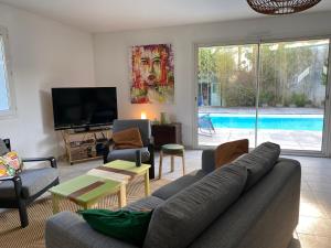 uma sala de estar com um sofá e uma televisão e uma piscina em Magnifique Maison Piscine Andernos sur le Bassin d'Arcachon ! em Andernos-les-Bains