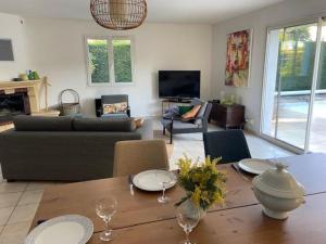 uma sala de estar com uma mesa e um sofá em Magnifique Maison Piscine Andernos sur le Bassin d'Arcachon ! em Andernos-les-Bains