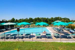 a pool with chairs and blue umbrellas at Il Casale Di Roma in Prima Porta