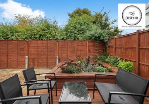 a patio with chairs and a wooden fence at Large 3 Bedroom House with Parking & Garden by Cherry Inn Short Let's & Services Accomodation in Cambridge