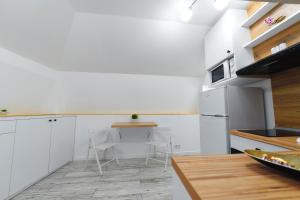 cocina con armarios blancos, mesa y sillas en Bella House, en Craiova