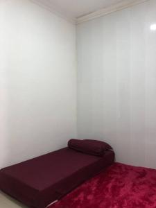 Cama en habitación con alfombra roja en Richandy House - 3 BR Full AC & Hot Water, en Kejayan
