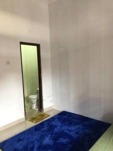 baño con alfombra azul y aseo en Richandy House - 3 BR Full AC & Hot Water, en Kejayan