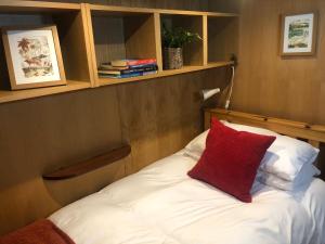 Una cama con una almohada roja encima. en Willow - Cottage on the River, Luxury Houseboat, en Little Baddow