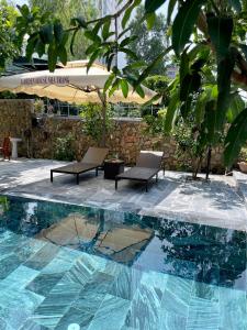 a swimming pool with two chairs and a table at Garden House Nha Trang in Nha Trang
