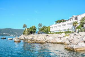 a body of water with rocks in front of a building at Hotel Perla - Annexes in Herceg-Novi