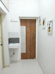 a bathroom with a wooden door and a sink at Meadows Homestay in Madurai