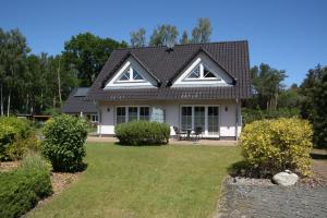 una casa blanca con techo negro en Trassenheide, Ferienidyll Neubauer, en Ostseebad Karlshagen
