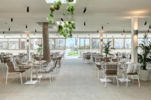 un comedor con mesas, sillas y ventanas en Utopia Blu Hotel, en Tigaki