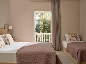 a hotel room with two beds and a window at Katerina Studios in Tsilivi