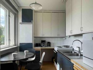 a kitchen with white cabinets and a table and a sink at Studiohuoneisto Liisankatu in Lappeenranta