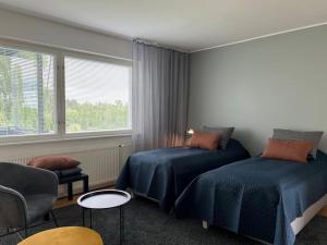 1 dormitorio con 2 camas, silla y ventana en Studiohuoneisto Liisankatu, en Lappeenranta