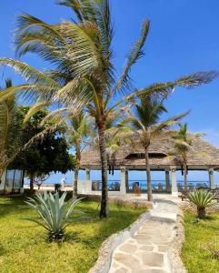 a palm tree next to a beach with a pavilion at Mawe Zuri Resort in Watamu