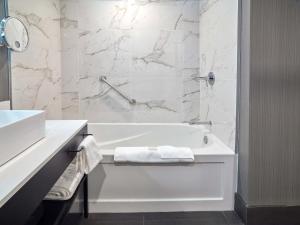 a white bathroom with a tub and a sink at Sandman Signature Plano-Frisco Hotel in Plano