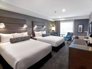 a hotel room with two beds and a desk at Sandman Signature Plano-Frisco Hotel in Plano