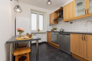 una cocina con armarios de madera y una mesa con flores. en Warsaw Praga Two-bedroom Apartment Kobielska by Renters, en Varsovia