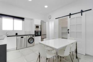 a white kitchen with a white table and chairs at Casa Manuela in Las Palmas de Gran Canaria