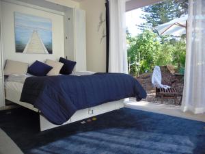 a bedroom with a bed and a large window at Blue Birds in Oneroa