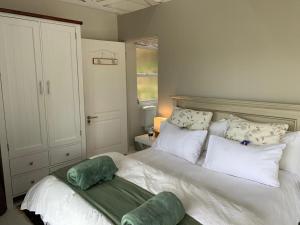 - une chambre avec un grand lit blanc et des oreillers blancs dans l'établissement Knysna Heads Private Suite, à Knysna