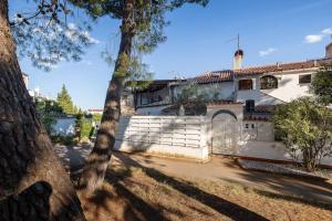 a white house with a gate and a tree at Pace e Salute in Barbariga