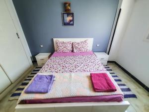 a small bedroom with a bed with purple and pink pillows at Sunshine House in Luxor