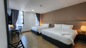 een hotelkamer met 2 bedden en een televisie bij Yu Hotel Chinatown in Kuala Lumpur
