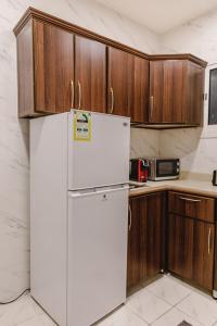 a white refrigerator in a kitchen with wooden cabinets at Al Butat Al Mummayza in Jeddah