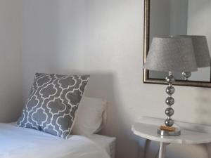 - une lampe sur une table à côté d'un lit avec un oreiller dans l'établissement @Oudam, à Montagu
