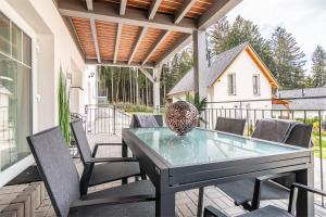 patio ze szklanym stołem i krzesłami w obiekcie Lipno - Lakeside Village - Větrník w mieście Frymburk